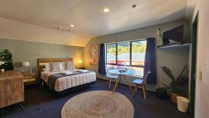 Franz Josef Montrose Lodge في فرانز جوزيف: غرفة نوم بسرير وطاولة ونافذة