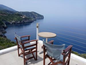 a table and chairs on a balcony with a view of the water at Kapetaniou Apartments in Limnionas