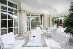 a lobby with white chairs and tables and columns at Grand Hotel Des Bains in Riccione