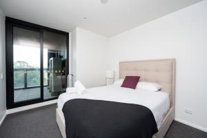 um quarto com uma cama grande e uma janela grande em Luxury Melbourne with Albert Park Views em Melbourne