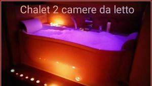 une baignoire avec des lumières violettes et les mots crak caméra da echo dans l'établissement Atmosfera e vista mozzafiato Chalets, à Aoste