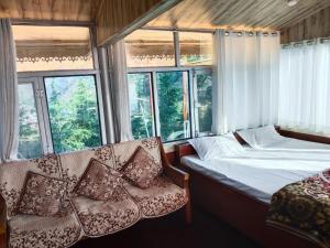 a bedroom with a bed and two chairs and windows at Gulab - B Homestay in Dehradun