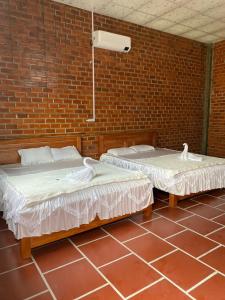 two beds in a room with a brick wall at Chau Doc Homestay in Chau Doc