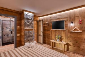 1 dormitorio con paneles de madera y TV en la pared en L'Arbergh Palanfrè, en Vernante