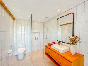 a bathroom with a sink and a mirror and a toilet at Villa Avocagolf Uluwatu by Nakula in Uluwatu