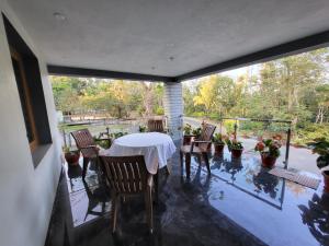 patio con mesa y sillas en el balcón en Charvi Villa Stay - 3BH, Home Food, Campfire, en Chikmagalur