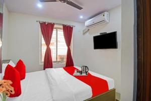 um quarto com uma cama vermelha e branca e uma televisão em GRG Vhyom Sky Palace Near Metro Station Kolkata em Calcutá
