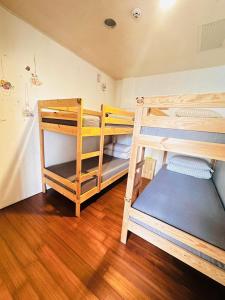 two bunk beds in a room with wooden floors at One House in Gongliao