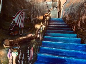 a stairway with blue stairs and a painting on the wall at One House in Gongliao