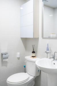 a white bathroom with a toilet and a sink at Goose Stay in Bucheon