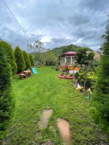a yard with a house in the background with trees at Vinland Villa Atalar in Trabzon