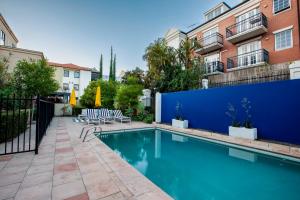 a swimming pool with chairs next to a building at Spacious Apt in Northbridge with Pool in Perth
