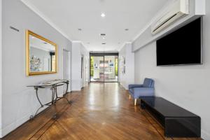 a living room with a tv and a blue couch at Spacious Apt in Northbridge with Pool in Perth