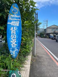 a blue surfboard on a bush next to a street at One House in Gongliao