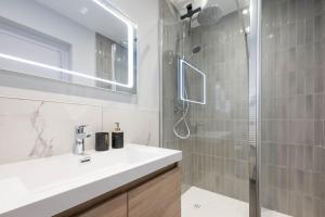 a bathroom with a sink and a glass shower at L'Opéra, T2 Cœur Ville in Anse