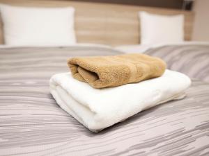 a pile of towels sitting on top of a bed at Hotel Route-Inn Shinjyo Ekimae in Shinjo