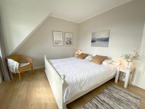 ein Schlafzimmer mit einem weißen Bett und einem Stuhl in der Unterkunft Ferienhaussiedlung Strandperlen Weidenhof 3b (Typ VI) in Wustrow