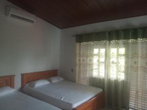 1 dormitorio con 2 camas y una ventana con cortinas en Rock Villa Relax City Home en Mihintale