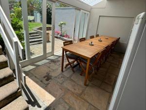a wooden table and chairs in a room with a balcony at Moments B&B Guesthouse, Kleinmond in Kleinmond