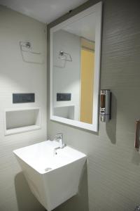 La salle de bains est pourvue d'un lavabo blanc et d'un miroir. dans l'établissement Tattvamasi Retreat, à Mumbai