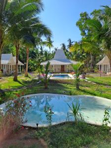 une piscine en face d'une maison avec des palmiers dans l'établissement The Palms Penida, à Toyapakeh