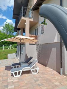 une chaise de plage et un parasol à côté d'un bâtiment dans l'établissement Vikendica Villa Ramona Banja Luka, à Banja Luka