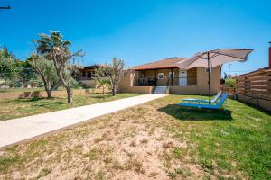 a yard with a blue bench and an umbrella at Flegra House in Nea Potidaea