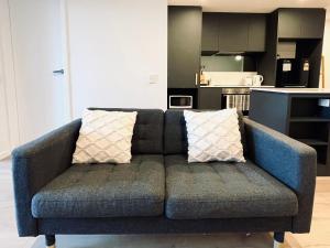1 sofá azul con 2 almohadas en la sala de estar en The Metropol 2BR Apt, In the heart of CBD 2b1b1c, Free parking, Wi-Fi en Canberra