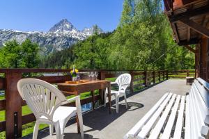 Un patio con dos sillas blancas y una mesa y bancos de madera. en MontBlanc Alpine Ski & Sauna Retreat - Happy Rentals, en Le Tour