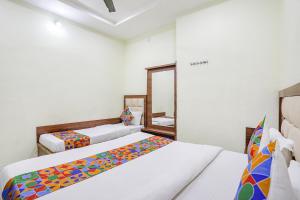 um quarto com 2 camas e um espelho em FabHotel Naresh Palace em Raipur