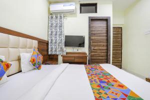 1 dormitorio con 1 cama grande y TV en FabHotel Naresh Palace en Raipur