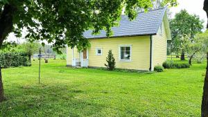 ein gelbes Haus in einem Garten mit einem Baum in der Unterkunft Nice holiday home in Balsta in Bålsta