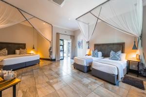 Habitación de hotel con 2 camas y mesa en Nkosi Guest Lodge en Victoria Falls