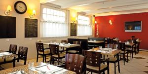 a restaurant with tables and chairs and a clock on the wall at L'Etoile d'Or in Chaumont