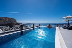 a swimming pool with a view of the ocean at Petit Palace Suites in Fira