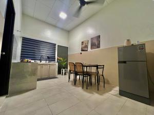 a kitchen with a table and chairs and a refrigerator at Corner House - Three Bedroom Quayside Rimbayu Kg Lombong Jalan Kebun Puchong in Shah Alam