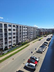 parking z samochodami zaparkowanymi przed dużym budynkiem w obiekcie Apartament Górska Szarotka w Nowym Targu