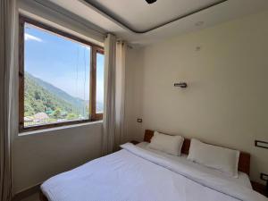 sypialnia z łóżkiem i dużym oknem w obiekcie Hide Out Stays w mieście Dharamsala