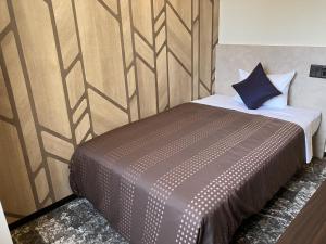 1 dormitorio con 1 cama con pared de madera en HOTEL LiVEMAX BUDGET Shinosaka en Osaka