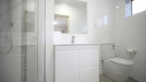 a white bathroom with a sink and a toilet at Apartment 5 - The Meridian in Old Bar +13 photos