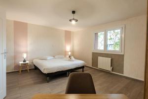 a bedroom with a bed and a window and a table at Belle maison rénovée avec jacuzzi in Saint-Rémy