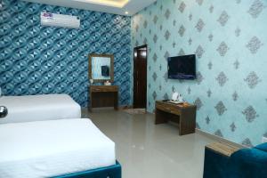 een slaapkamer met een bed en een televisie en een spiegel bij Hotel Grand Pearl in Lahore