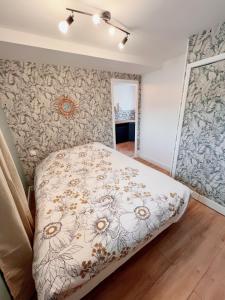 a bedroom with a bed with a floral patterned wall at Maison T3 2CH Climatisée Terrasse parking gratuit in Saint-Julien-les-Villas