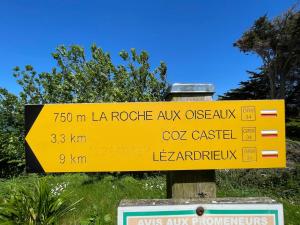 a yellow sign on a pole in the grass at Maison de pêcheur Loguivy de la mer in Ploubazlanec