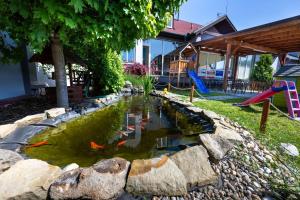 烏赫爾布羅德的住宿－Hotel & SPA centrum PALMIRA，庭院里的锦 ⁇ 池塘,带游乐场