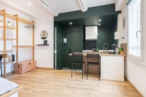 une cuisine avec des murs verts et un comptoir avec des tabourets dans l'établissement Le Cocon de Grignan, à Marseille 17 autres photos