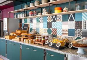 a kitchen with blue cabinets and a tile wall at B&B HOME Paris Mairie de Saint-Ouen in Saint-Ouen