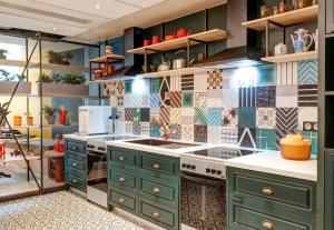 a kitchen with green cabinets and tiles on the wall at B&B HOME Paris Mairie de Saint-Ouen in Saint-Ouen