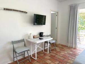 ハベアにあるHabitación con jardín y terraza en el Tosaletのテーブルと椅子2脚、壁掛けテレビが備わる客室です。