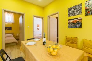 una habitación amarilla con una mesa con un bol de fruta. en Folklore House in Historical Catania - Happy Rentals, en Catania